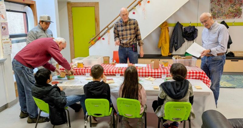 Project leaders demonstrate how to assemble a wooden box, sharing skills and knowledge with youth participants.